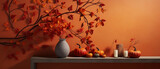 Jesienna dekoracja domu z gałązek i liści klonu na tle pomarańczowej ściany oraz stolik z dyniami, wazonami i świecami