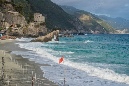 Fototapeta Naklejka Na Ścianę i Meble -  Red flag and sea waves on Fegina beach, Monterosso al Mare ITALY