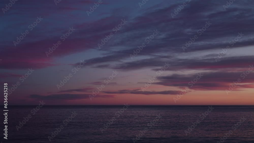 Beautiful sunset zoom shot with purple clouds and flying birds over the sea Beautiful sunset zoom shot with purple clouds and flying birds over the sea