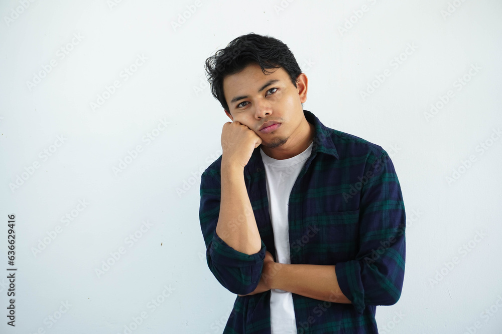 young asian man showing gloomy expression by placing a fist on the cheek isolated on white background young asian man showing gloomy expression by placing a fist on the cheek isolated on white background