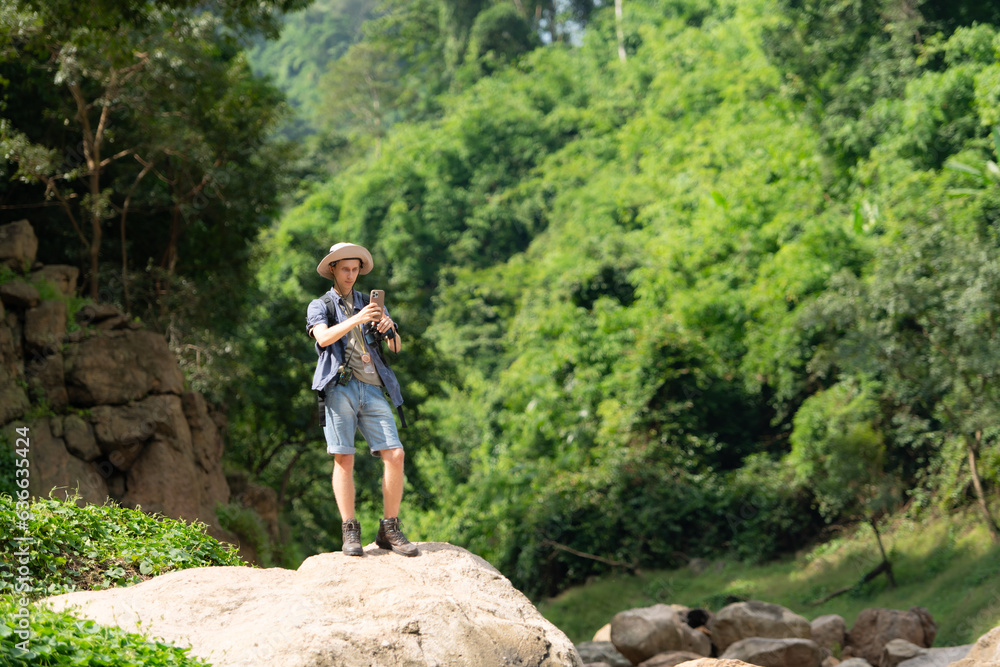 Young man with backpack hiking in the forest. Active lifestyle concept.