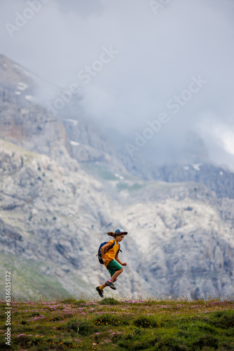 boy with a backpack on a hike against the backdrop of the mountains. child traveler with backpack, hiking, travel, mountains in the background, kids summer vacation.