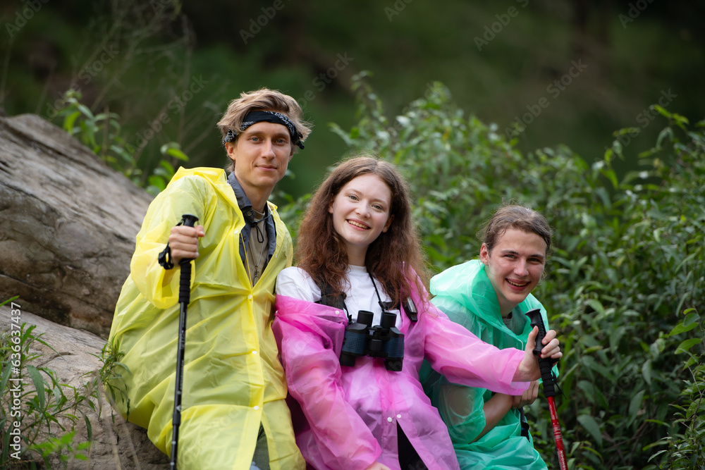 Group of friends in raincoats with backpacks on a hike in the forest, Prepare to hiking after the rain has stopped. Group of friends in raincoats with backpacks on a hike in the forest, Prepare to hiking after the rain has stopped.