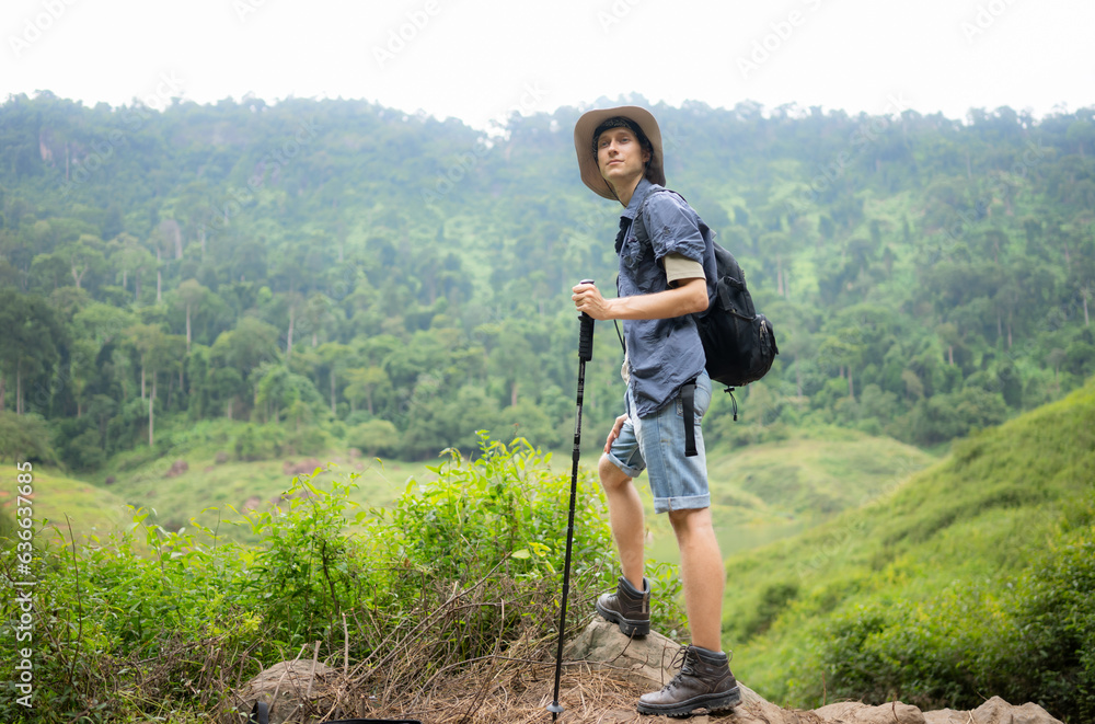 Young man with backpack hiking in the forest. Active lifestyle concept.