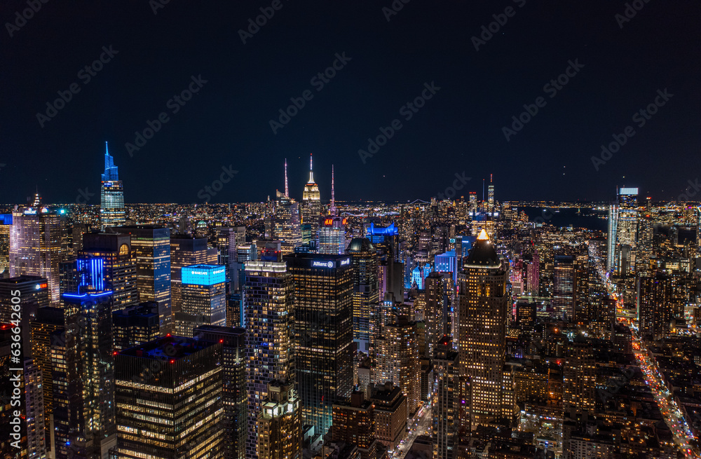 Aerial panoramic shot of metropolis at night. Colourful neon lights on high rise buildings in urban borough. Manhattan, New York City, USA
