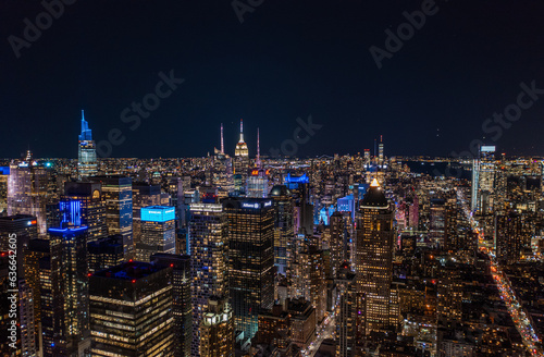 Aerial panoramic shot of metropolis at night. Colourful neon lights on high rise buildings in urban borough. Manhattan  New York City  USA
