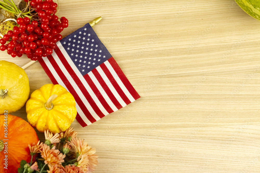 Obraz premium Autumn card with vegetables, gardens, flowers and usa flag on wooden background. Thanksgiving and Halloween holiday card. Autumn background with copy space. High quality photo
