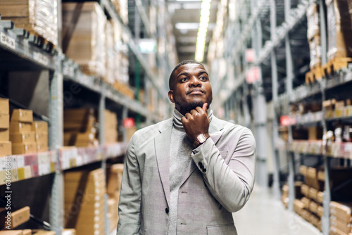 Portrait of smiling african american business man order details on tablet checking goods and supplies on shelves with goods background in warehouse.logistic and business export