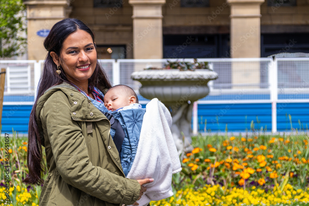 Latin woman with her baby in a baby carrier, in a park