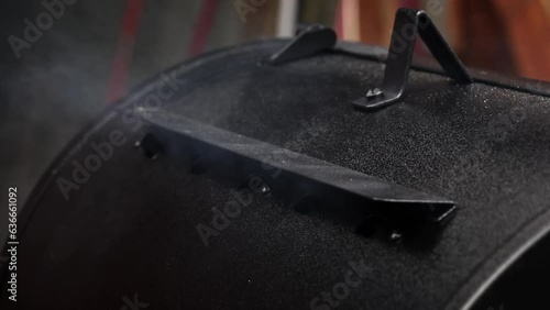 Smoke coming out of a smokestack of a small black smoker grill or barbecue on slow motion