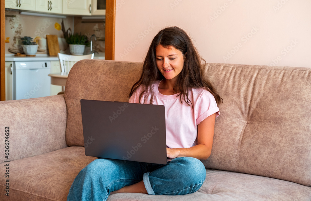 Beautiful woman using computer sitting on sofa at home. Beautiful woman using computer sitting on sofa at home.