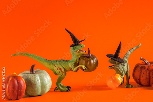 Two cute happy dinosaurs with pumpkins on orange background.