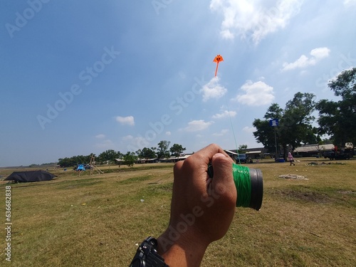 The hand is playing the kite while holding the kite string