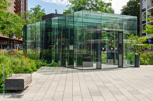 Enschede, The Netherlands, August 9, 2023: glass facades of the entry to the parking garage under Koningsplein square, surrounded by lots of greenery photo