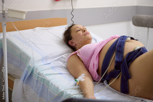Pregnant birthing mother woman has contractions, checks the heartbeat and pulse of her baby, using an electrocardiogram