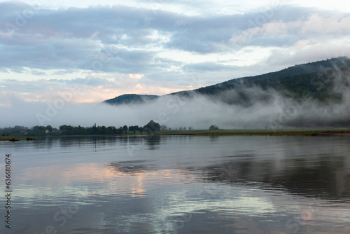 Dramatic misty sunrise sky with clouds in pink and blue tones over the Gouffre River, Baie-Saint-Paul, Charlevoix, Quebec, Canada © Anne Richard