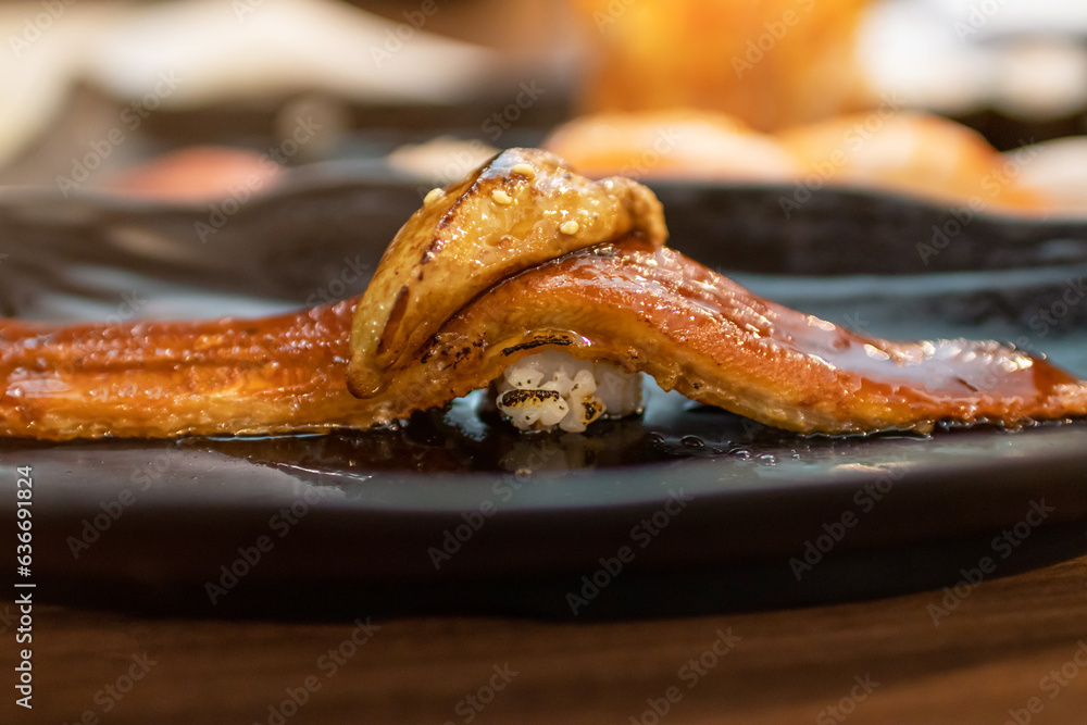 Delicious Unagi nigiri sushi (Eel Sushi) with foie gras on top on black plate. Traditional Japanese cuisine. Delicious Unagi nigiri sushi (Eel Sushi) with foie gras on top on black plate. Traditional Japanese cuisine.