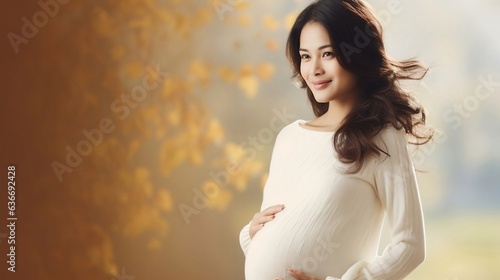 Beautiful pregnant asian woman in the autumn park. Happy pregnancy concept.