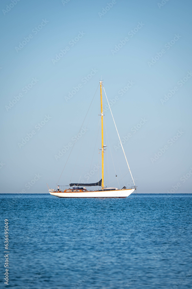 Piccola barca a vela illuminata dalla prima luce del mattino - Risveglio all'alba sul mare di Sardegna Piccola barca a vela illuminata dalla prima luce del mattino - Risveglio all'alba sul mare di Sardegna