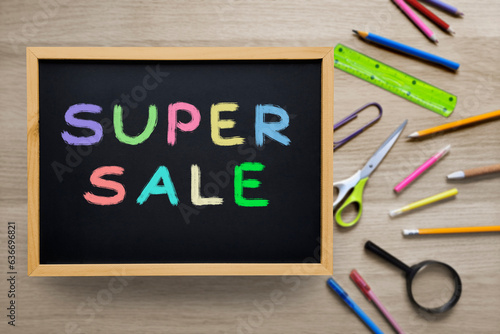 Sale of school supplies and stationery. Super sale text written with colored crayons on black chalkboard. Concept of back to school and preparation for the new school year. Template for advertising.