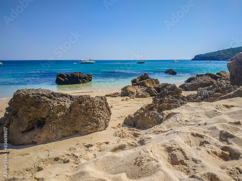 Rocks and sand on Galapos beach with yachts on the horizon in Natural Park of Serra da Arrábida, Setúbal PORTUGAL photo