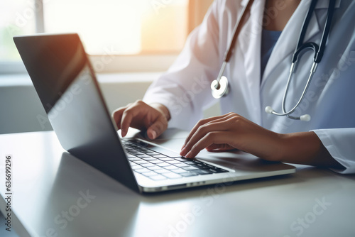 Close up of female doctor typing on laptop computer in medical office.