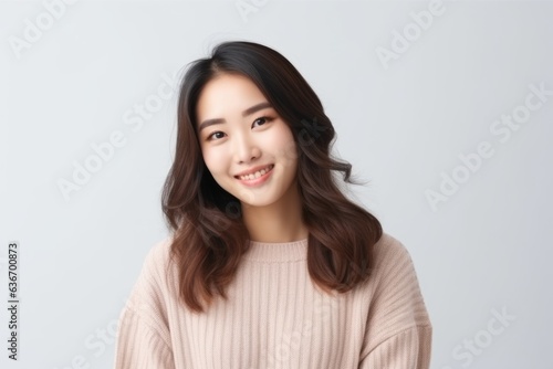 Medium shot portrait of a Chinese woman in her 20s in a white background wearing a cozy sweater © Anne-Marie Albrecht