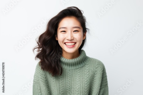 Lifestyle portrait of a Chinese woman in her 20s in a white background wearing a cozy sweater © Anne-Marie Albrecht