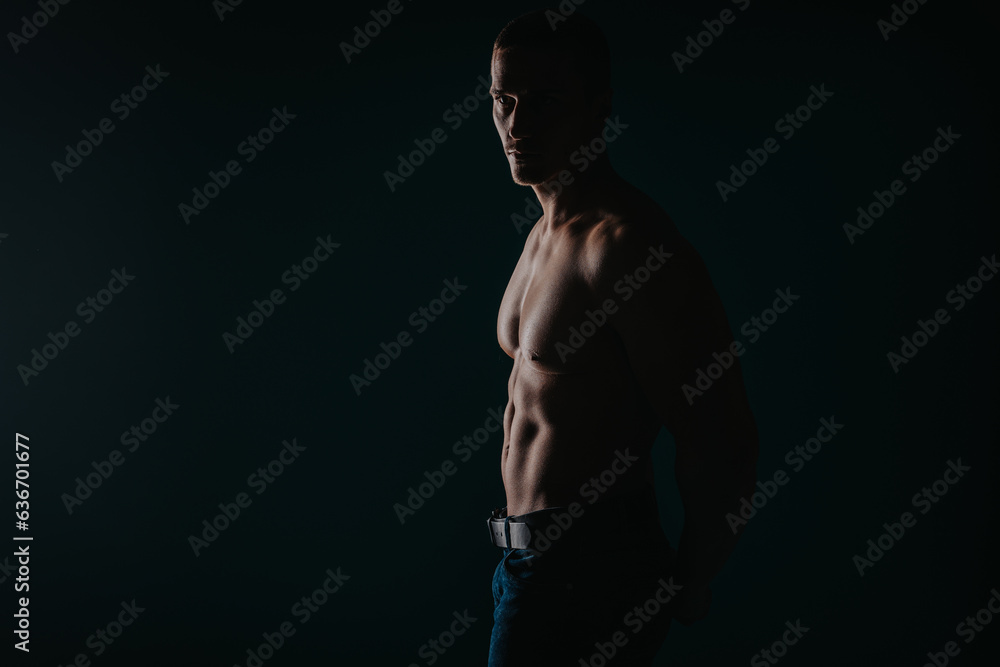 Silhouette shot of strong man showing his abs while looking away. Studio shot