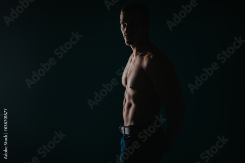 Silhouette shot of strong man showing his abs while looking away. Studio shot © qunica.com