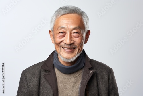 Lifestyle portrait of a Chinese man in his 70s in a white background wearing a chic cardigan