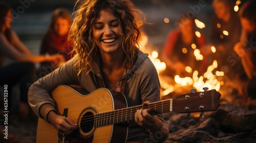 Fototapeta Naklejka Na Ścianę i Meble -  Young people gathered around a fire on the beach at night, having fun accompanied by guitars.