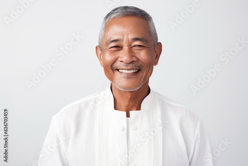 Medium shot portrait of a Indonesian man in his 50s in a white background wearing a chic cardigan
