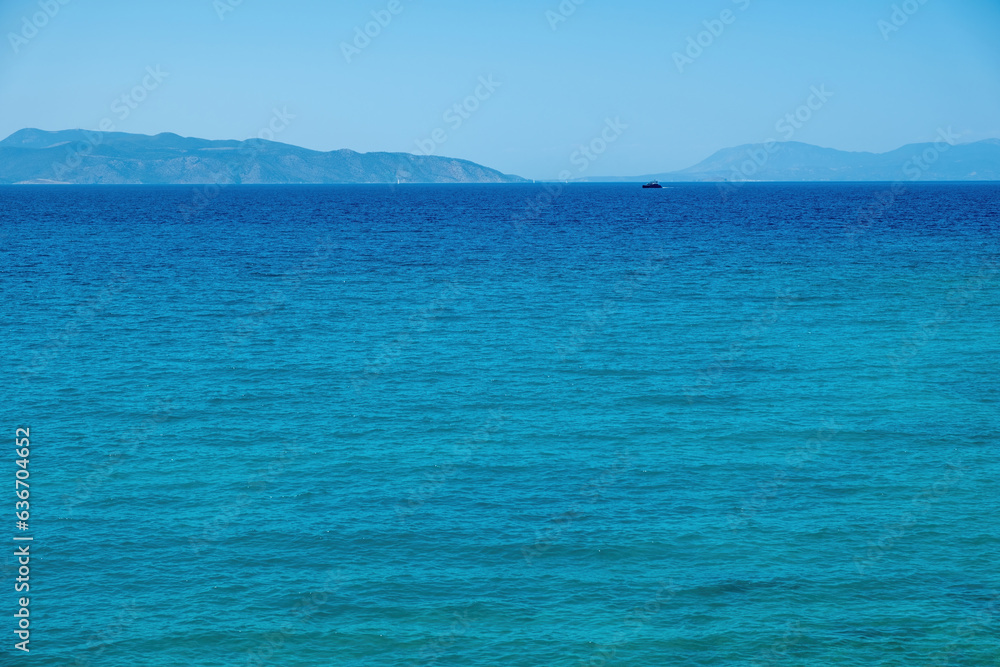 Ship sails in vast Mediterranean sea under Greek blue sky background. Summer destination, space.