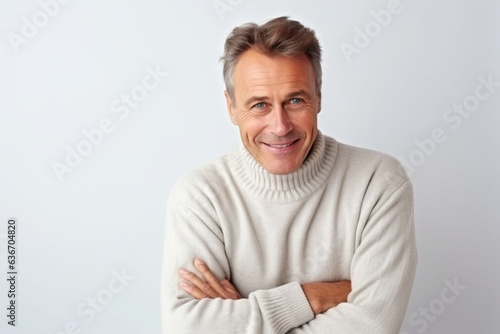 Medium shot portrait of a Russian man in his 50s in a white background wearing a cozy sweater © Anne-Marie Albrecht