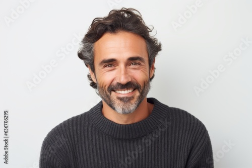 Lifestyle portrait of a Brazilian man in his 40s in a white background wearing a cozy sweater
