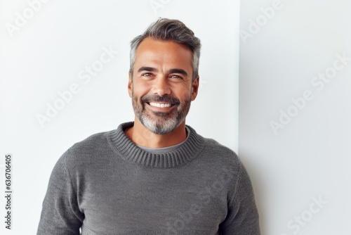Lifestyle portrait of a Brazilian man in his 40s in a white background wearing a chic cardigan