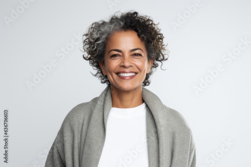 Medium shot portrait of a Brazilian woman in her 50s in a white background wearing a chic cardigan