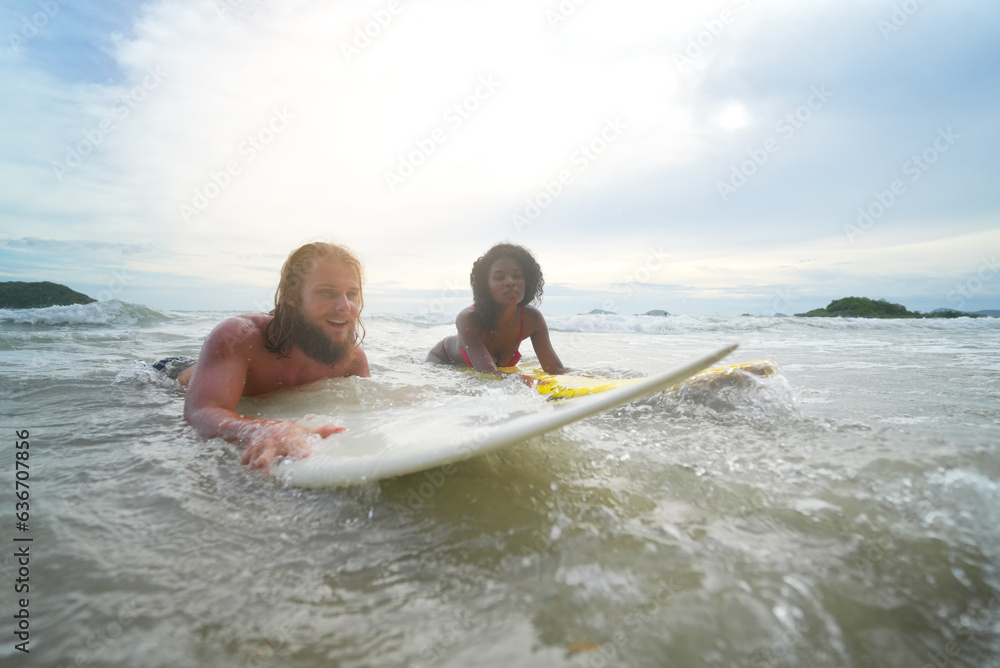 Happy couple surfing together on beach with surfing board in Pattaya, Thailand.