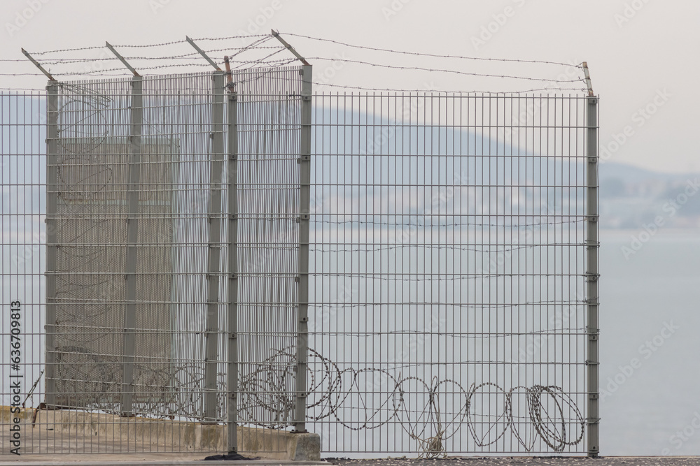 Barbed wire fencing over the sea, cloudy weather Barbed wire fencing over the sea, cloudy weather