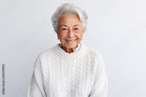 Portrait of smiling senior woman in sweater looking at camera over white background