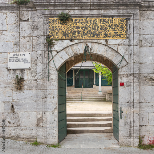 Arched entrance with open green metal door in brick stone wall leading to 17th century Cinili Mosque in Uskudar, Istanbul, Turkey photo