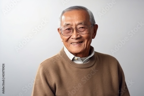 Portrait of senior asian man in brown sweater on white background © Anne-Marie Albrecht
