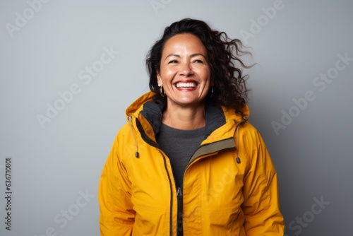 Portrait of a happy woman in a yellow jacket on a gray background