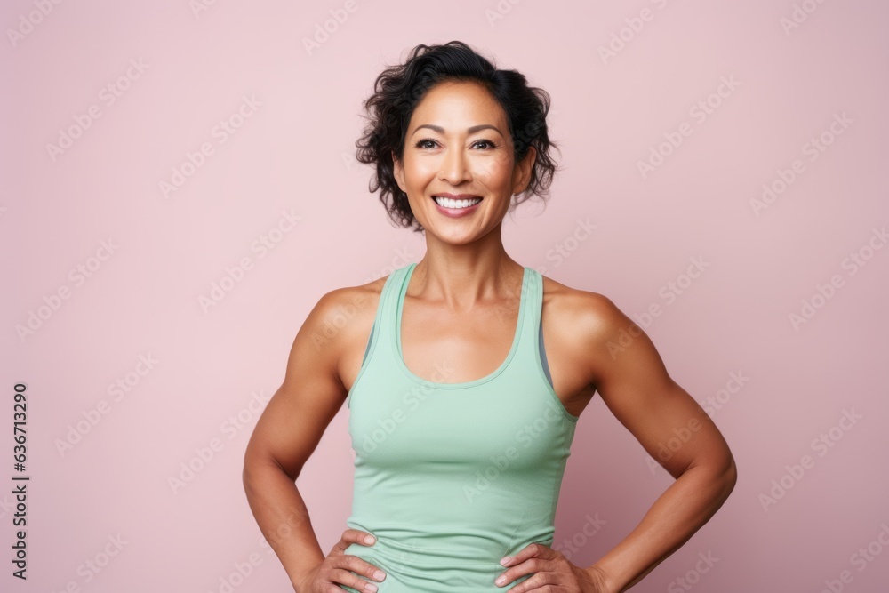 Portrait of a smiling fitness woman standing with hands on hips over pink background Portrait of a smiling fitness woman standing with hands on hips over pink background