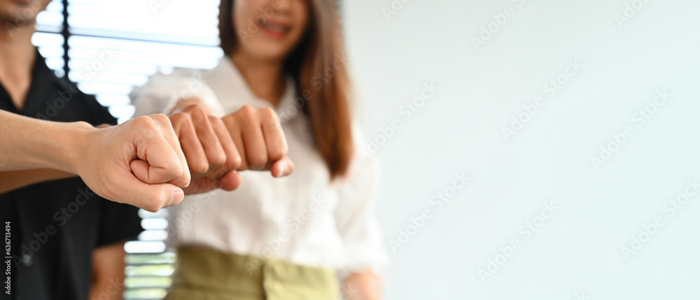 Close-up image of a group of mix aged creative workers bumping fists together, co-working, and unity concept, Ready to hit every problem.