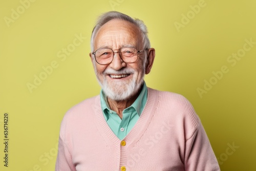 Portrait of a happy senior man with glasses on a yellow background