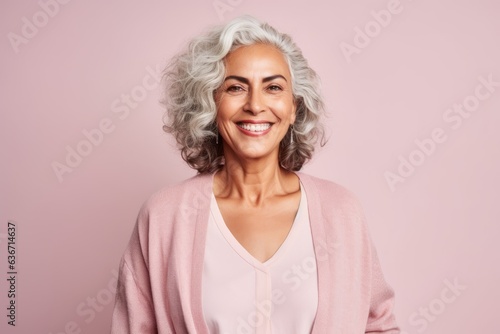 Portrait of a beautiful senior woman smiling at the camera while standing against pink background