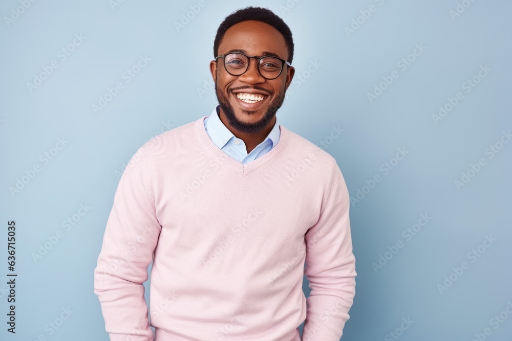 Fototapeta premium Medium shot portrait of a Nigerian man in his 30s in a pastel or soft colors background wearing a chic cardigan