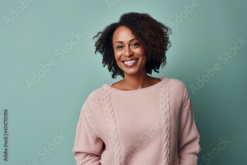 Lifestyle portrait of a Nigerian woman in her 40s in a pastel or soft colors background wearing a cozy sweater © Anne-Marie Albrecht